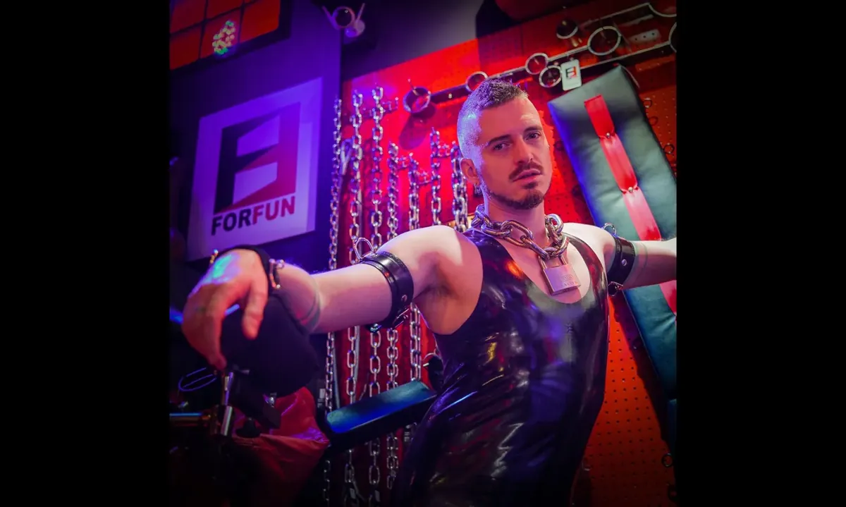 Axel Abysse still: a performer in a leather harness on a chain-lined set